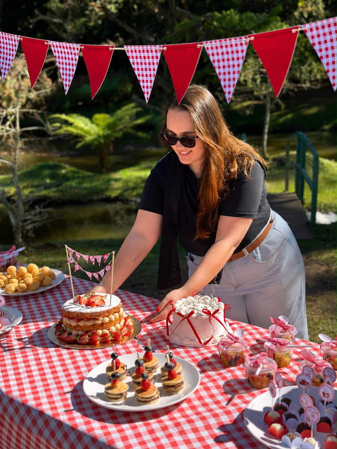 Nah organizando a mesa de doces com naked cake de morango e bolo decorado ao ar livre